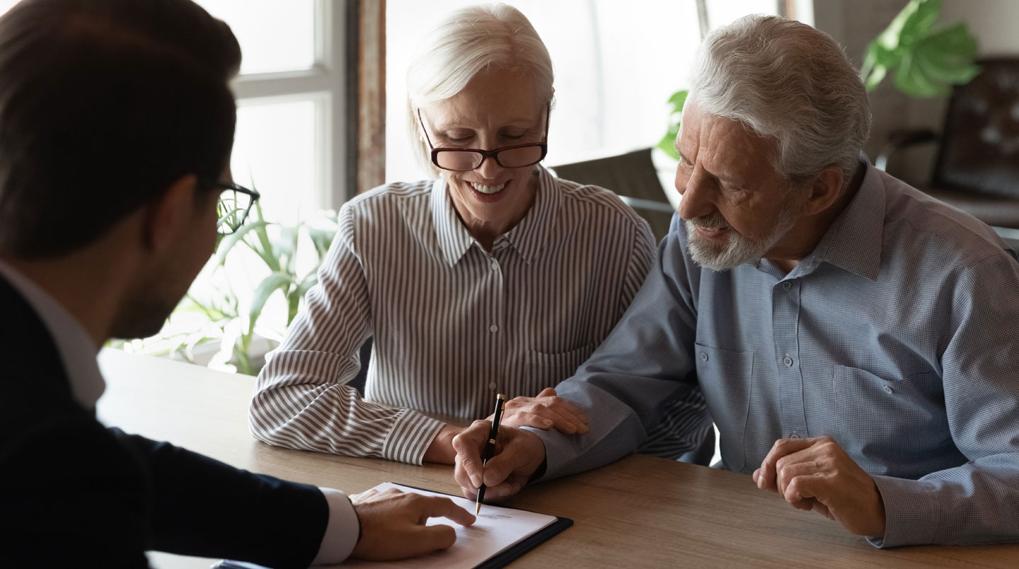 Espace commun d'une résidence services moderne avec larges baies vitrées, canapés contemporains et seniors en arrière-plan flou discutant naturellement